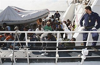 Rescued migrants are seen at an Italian coast guard boat while arriving at the port of Tripoli
